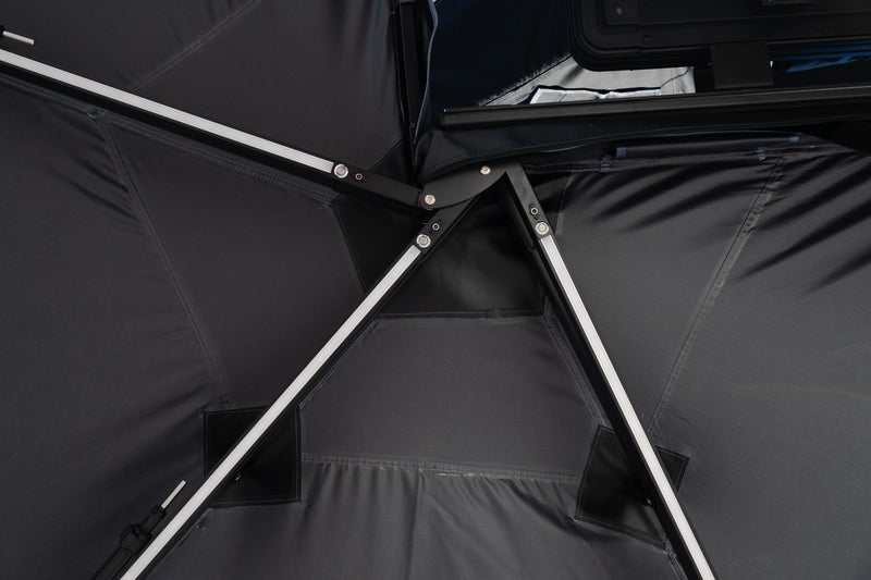 Load image into Gallery viewer, Close-up of a black Awning interior with silver metal support poles and dark fabric panels.
