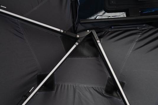 Close-up of a black Awning interior with silver metal support poles and dark fabric panels.
