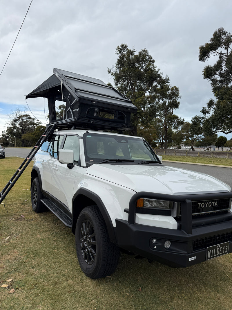 Load image into Gallery viewer, White SUV with an open roof rack on a grassy area with trees in the background
