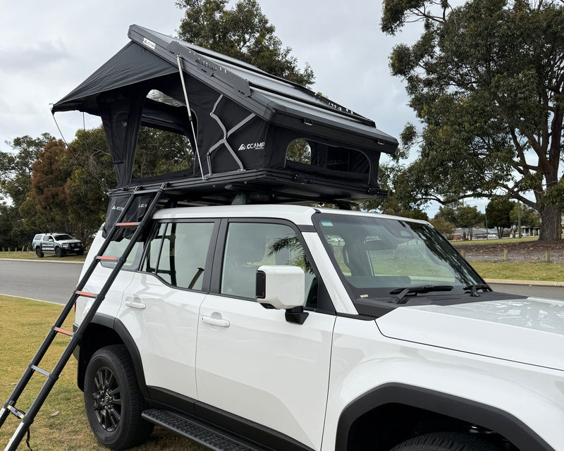 Load image into Gallery viewer, White SUV with an open roof rack on a grassy area with trees in the background
