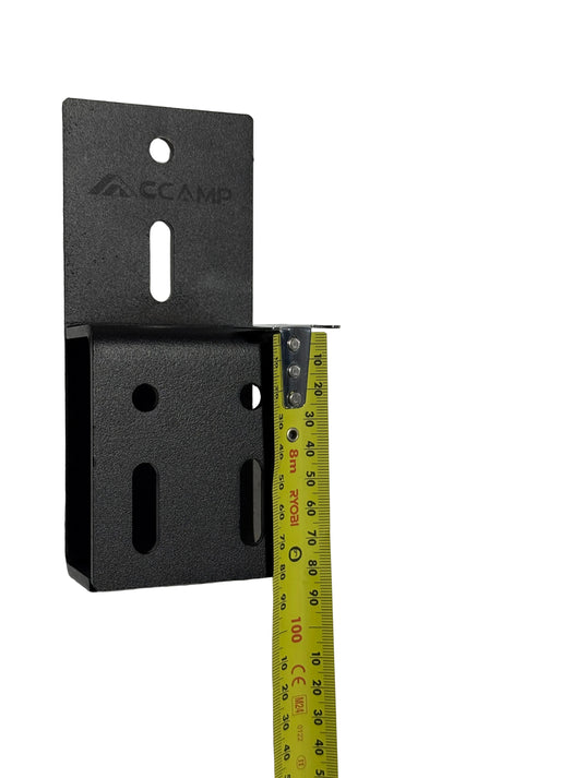 Black metal bracket with a measuring tape showing its dimensions on a gray surface