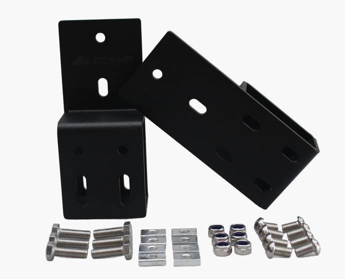 Black metal brackets and small metal components on a white surface with a white wall background.