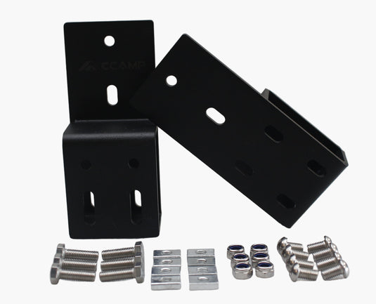 Black metal brackets and small metal components on a white surface with a white wall background.