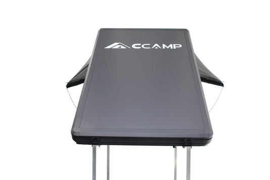 Black folding table with 'CCAMP' branding on a white background